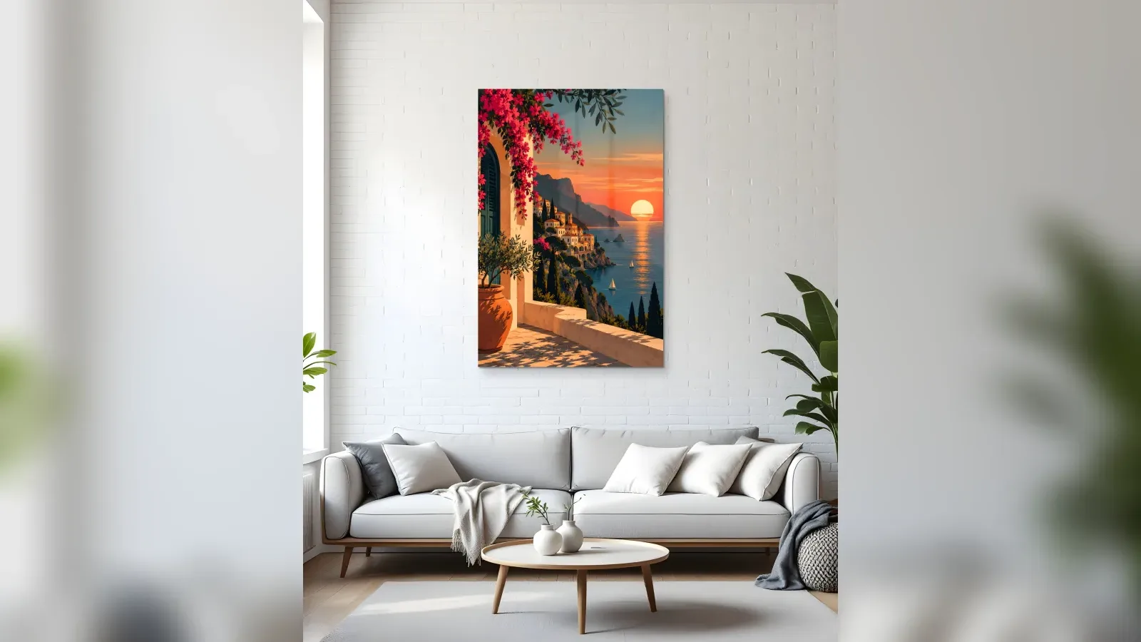 Beyaz kanepeli açık renkli bir oturma odasında duvara asılmış, gün batımında Akdeniz kıyısı manzaralı dikey cam tablo